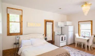 queen bed with stove, fridge and breakfast nook in vacation rental
